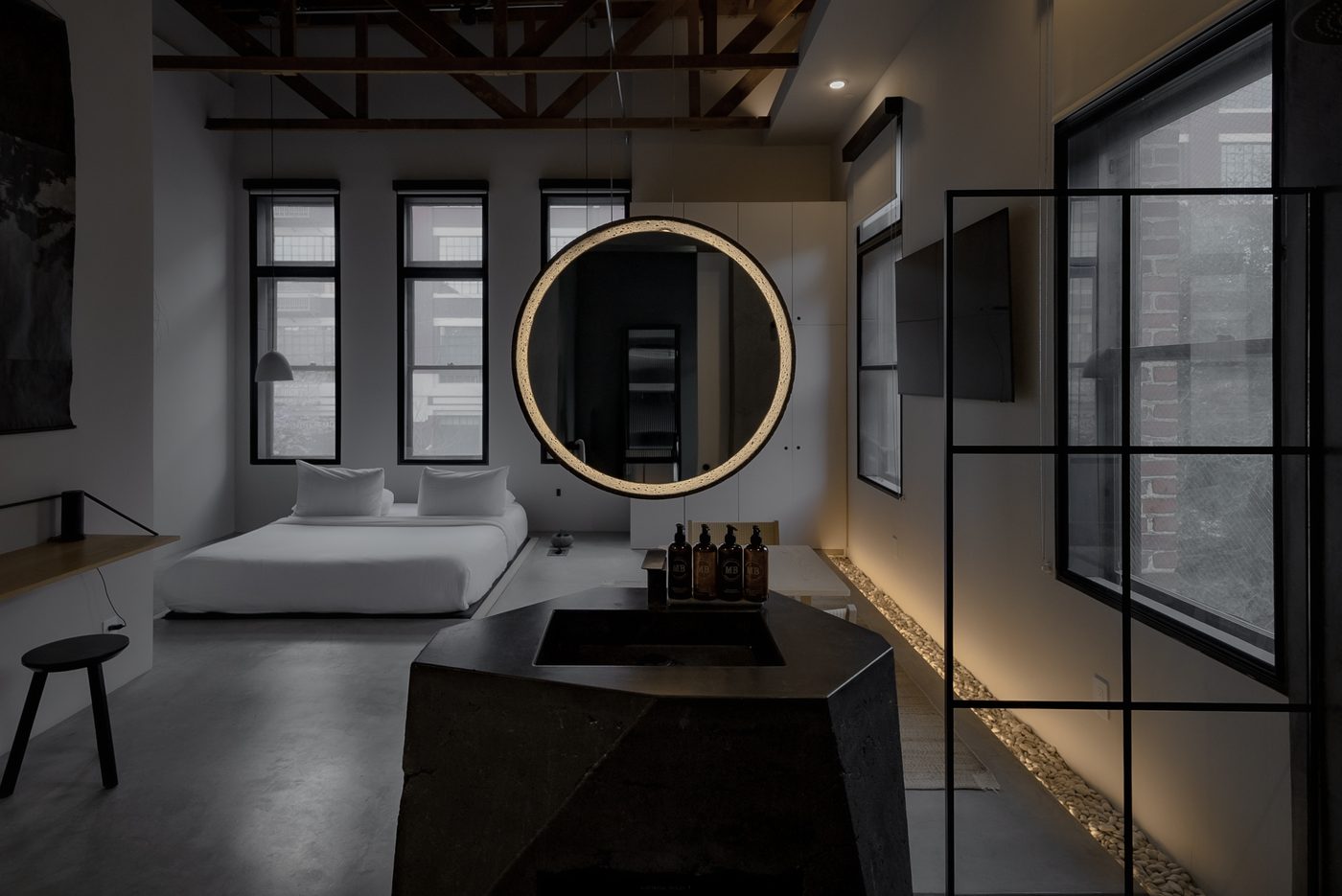 A dark suite with a round mirror and a steel framed window